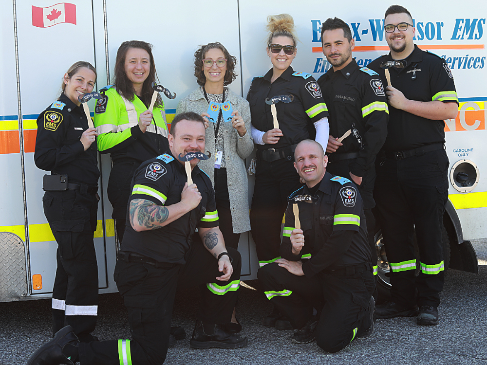 Paramedics with mock moustaches in front of an ambulance!