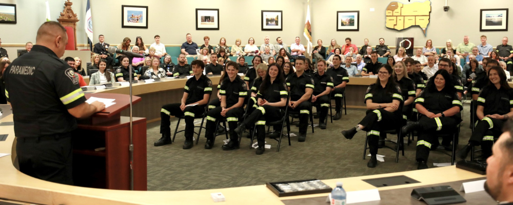 Paramedics and family members listen to a paramedic speak in Council Chambers