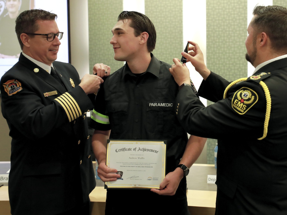 Fire Chief James Waffle attaches epaulettes to a new paramedic's uniform