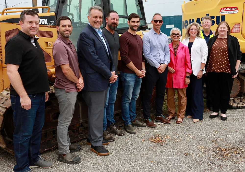 Warden Hilda MacDonald and County of Essex staff and contractor representative pose by a piece of heavy machinery.