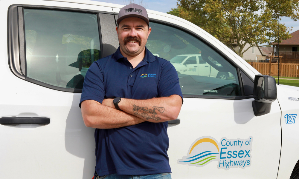 Shane Beausoleil with arms crossed in front of a County of Essex truck