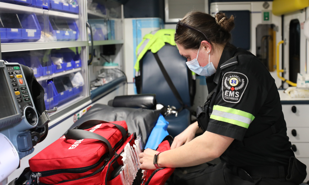 A primary care paramedic checks supplies and equipment in the back of an ambulance.