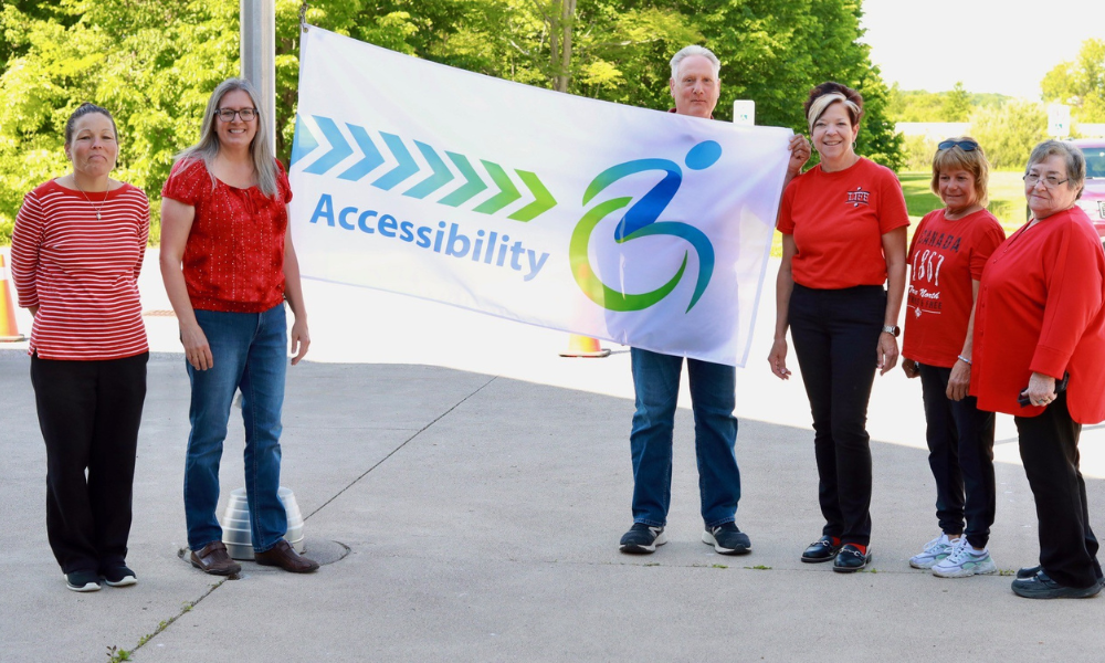 Members of the Essex County Accessibility Advisory Committee hold the Accessibility flag by the pole