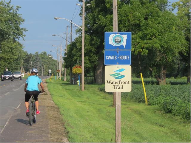 A cyclist rolls by a CWATS sign