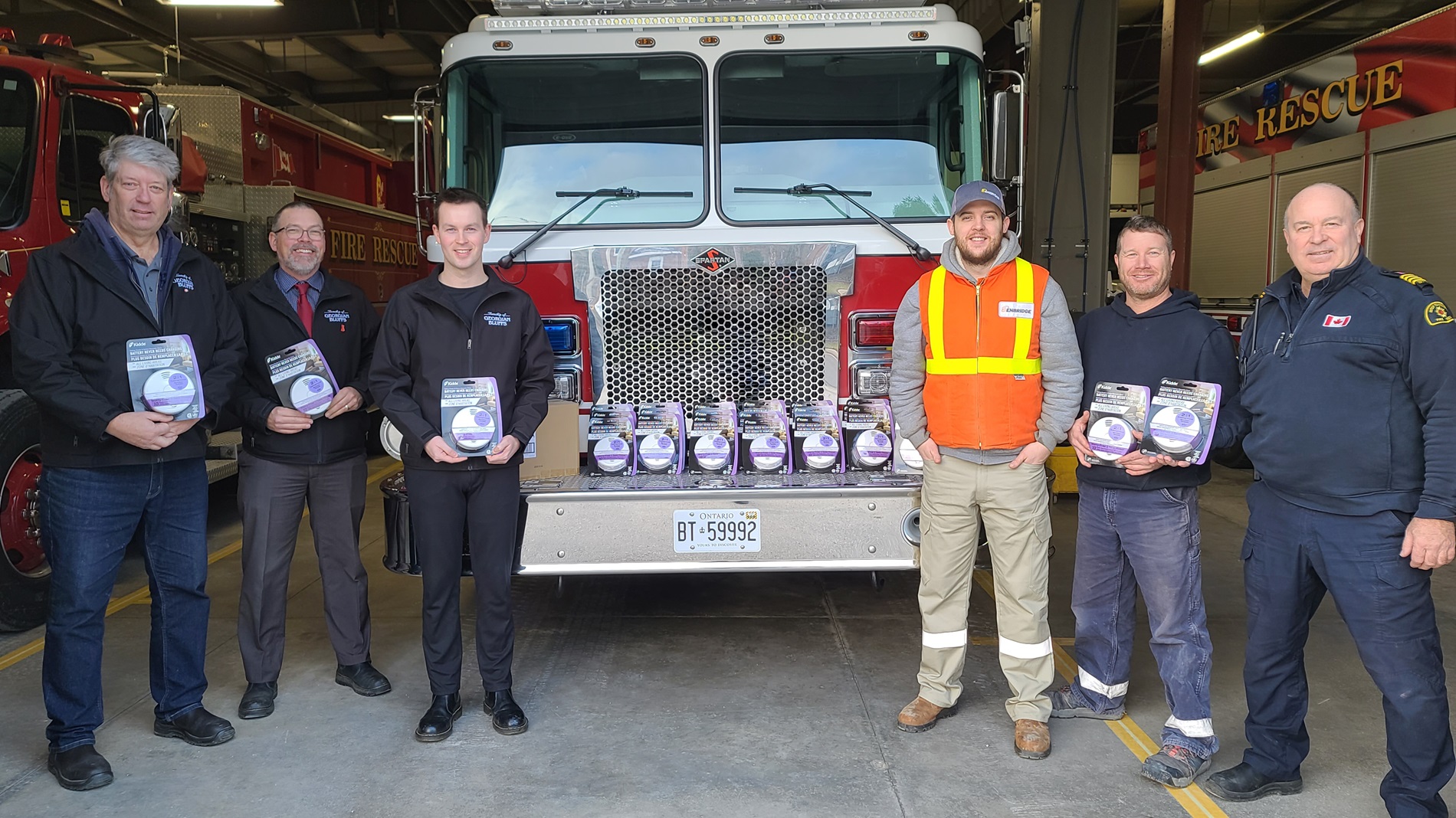 People holding smoke alarms around a fire truck