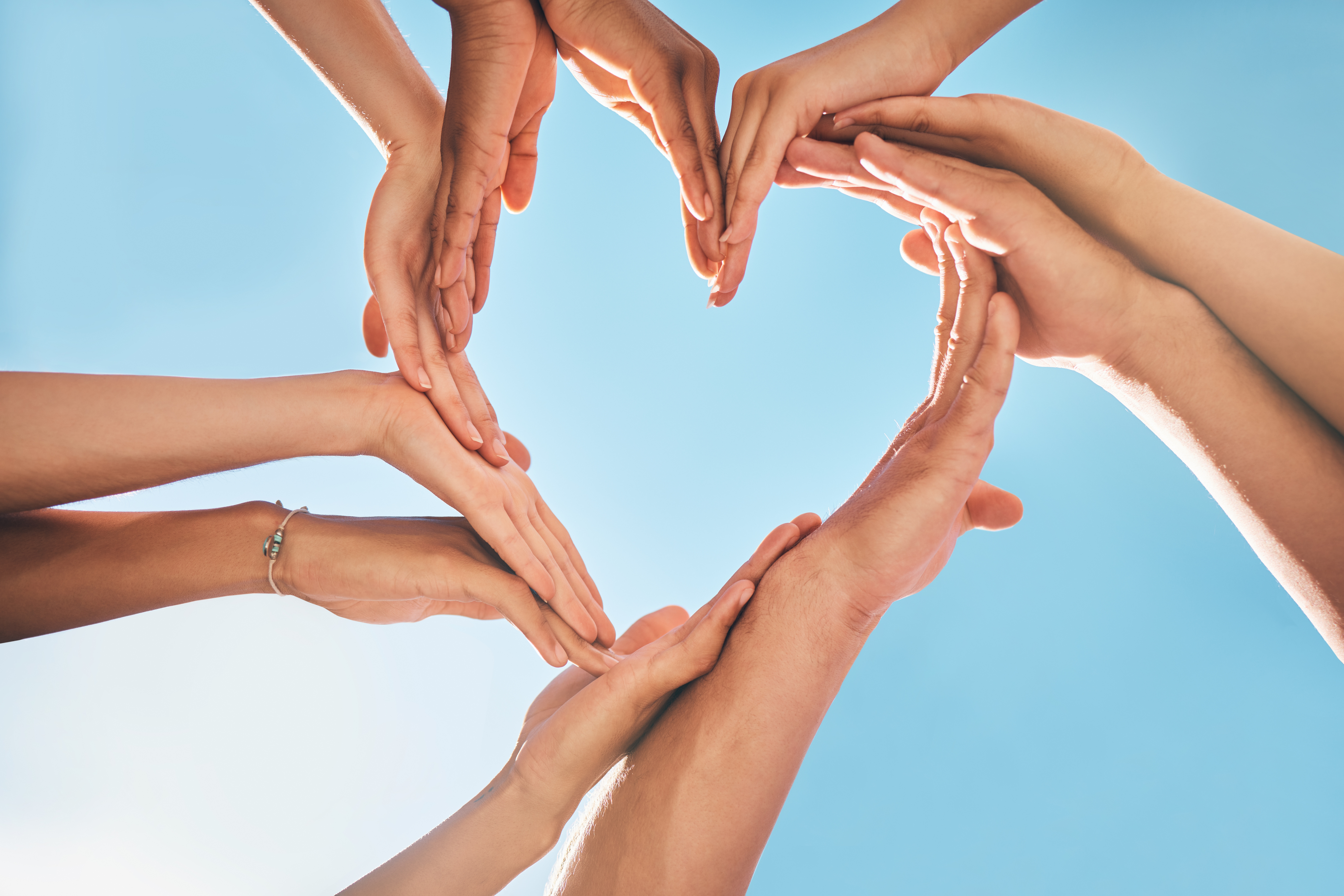 Group of hands in the shape of a heart.