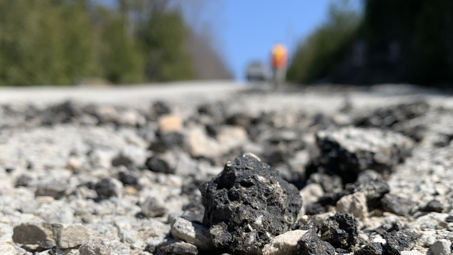 a pothole with a high-vis worker in the background