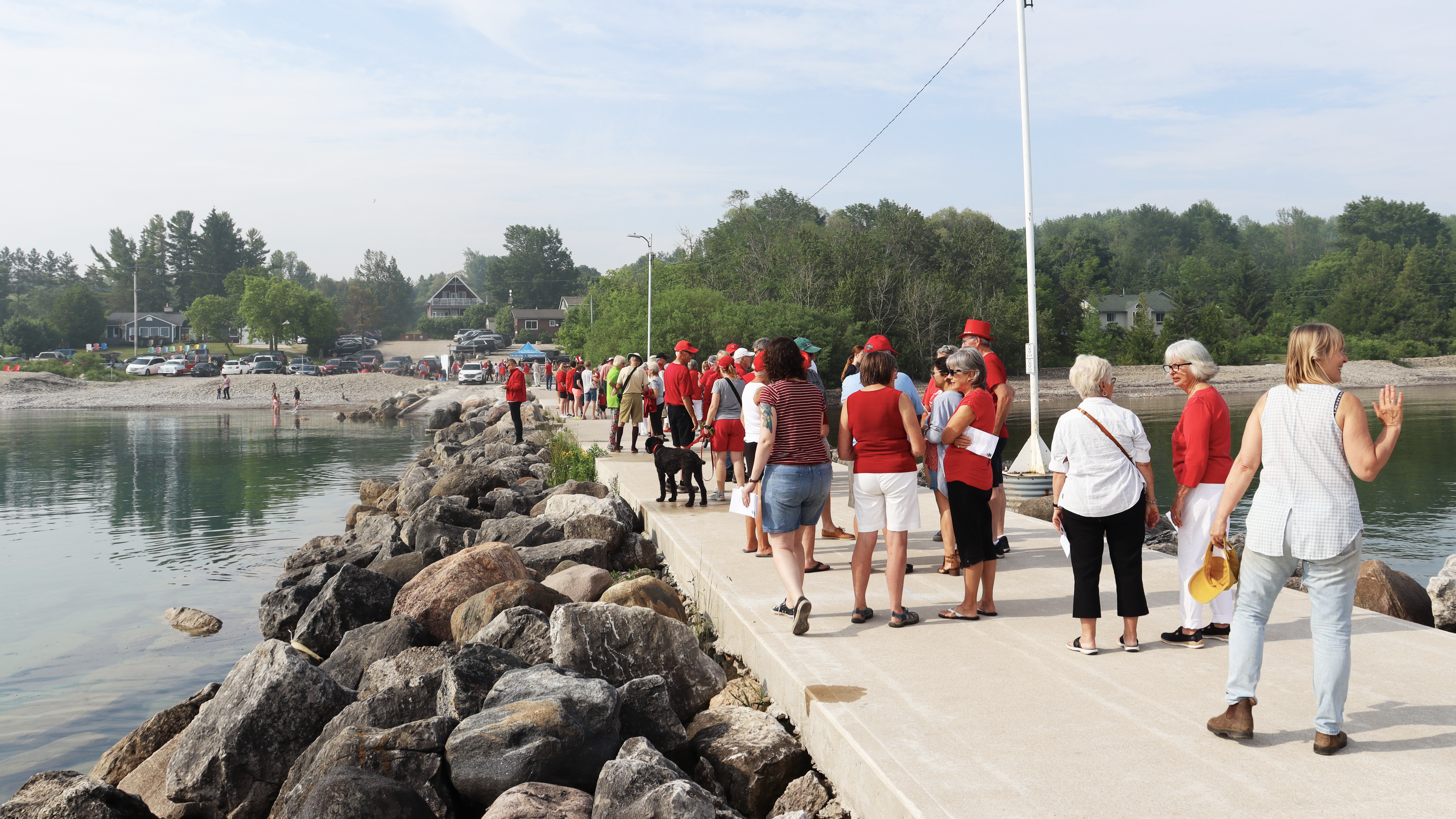 A crowd of people wearing red on a sunny pier