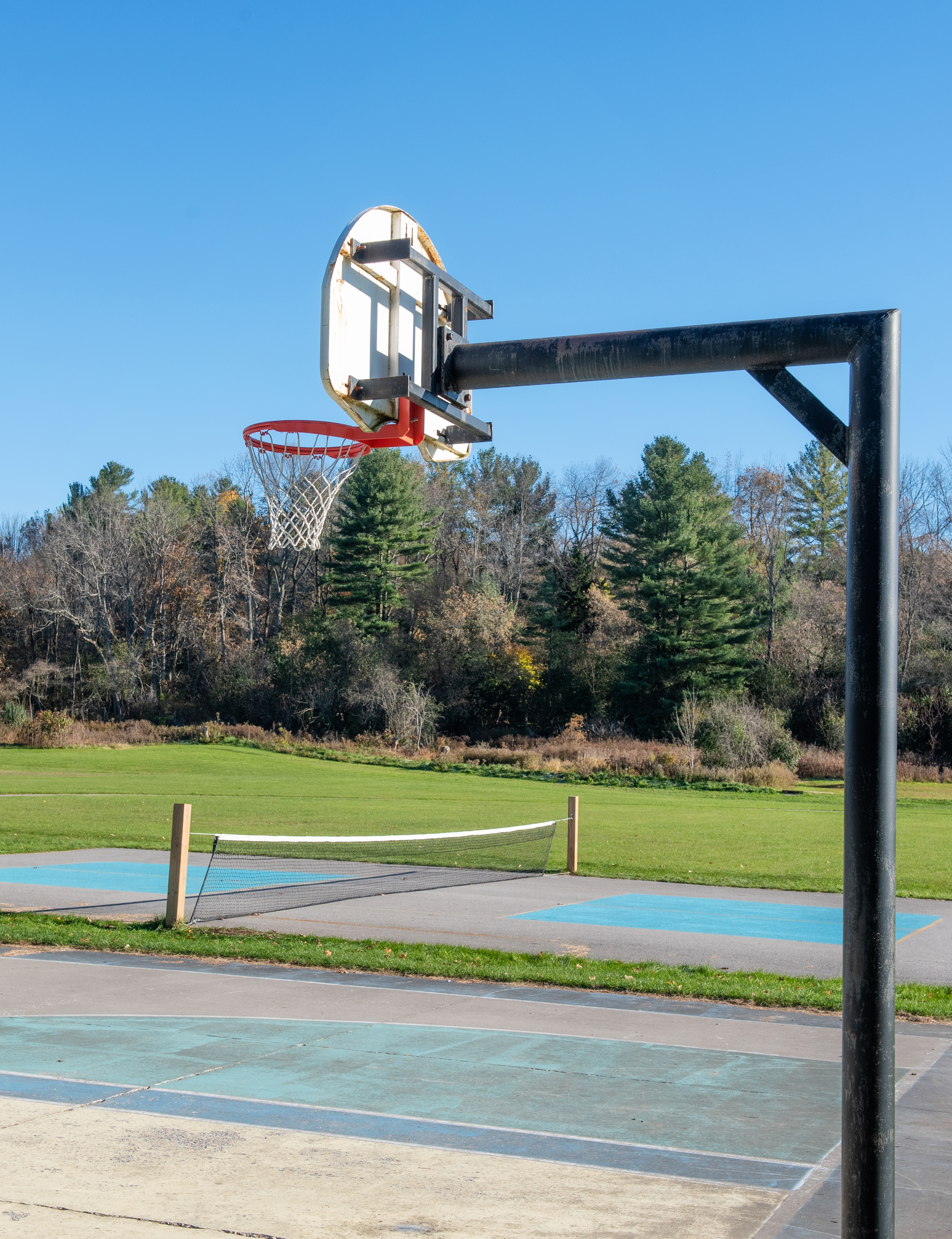 outdoor basketball court focused on the basket with a pickleball court in the background
