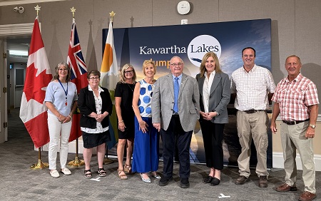 Group photo in front of brand banner for Omemee Arena project grant announcement