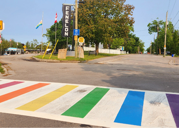 Street view with a crosswalk with rainbow stripes in the foreground.