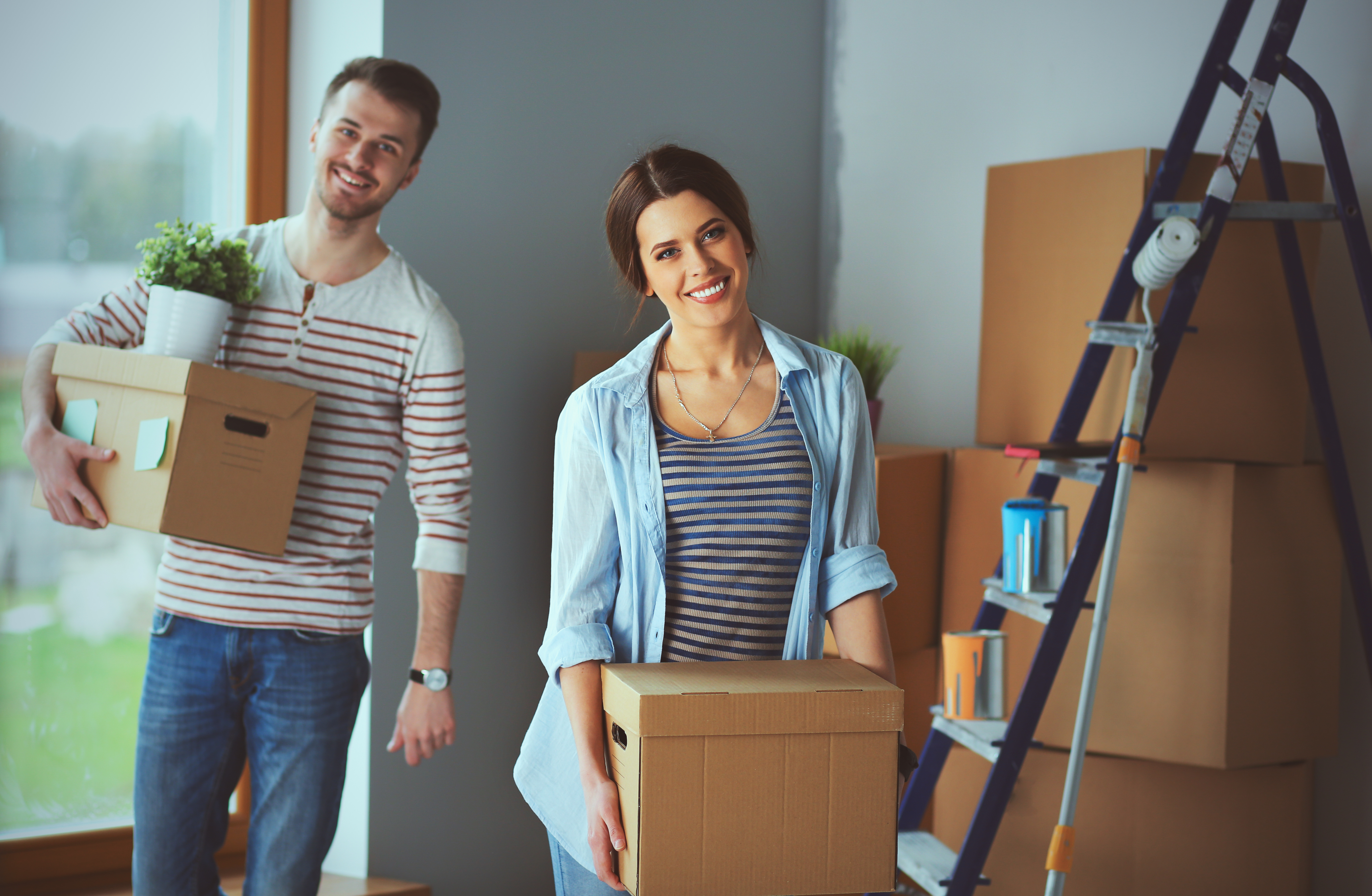 Two people moving boxes inside