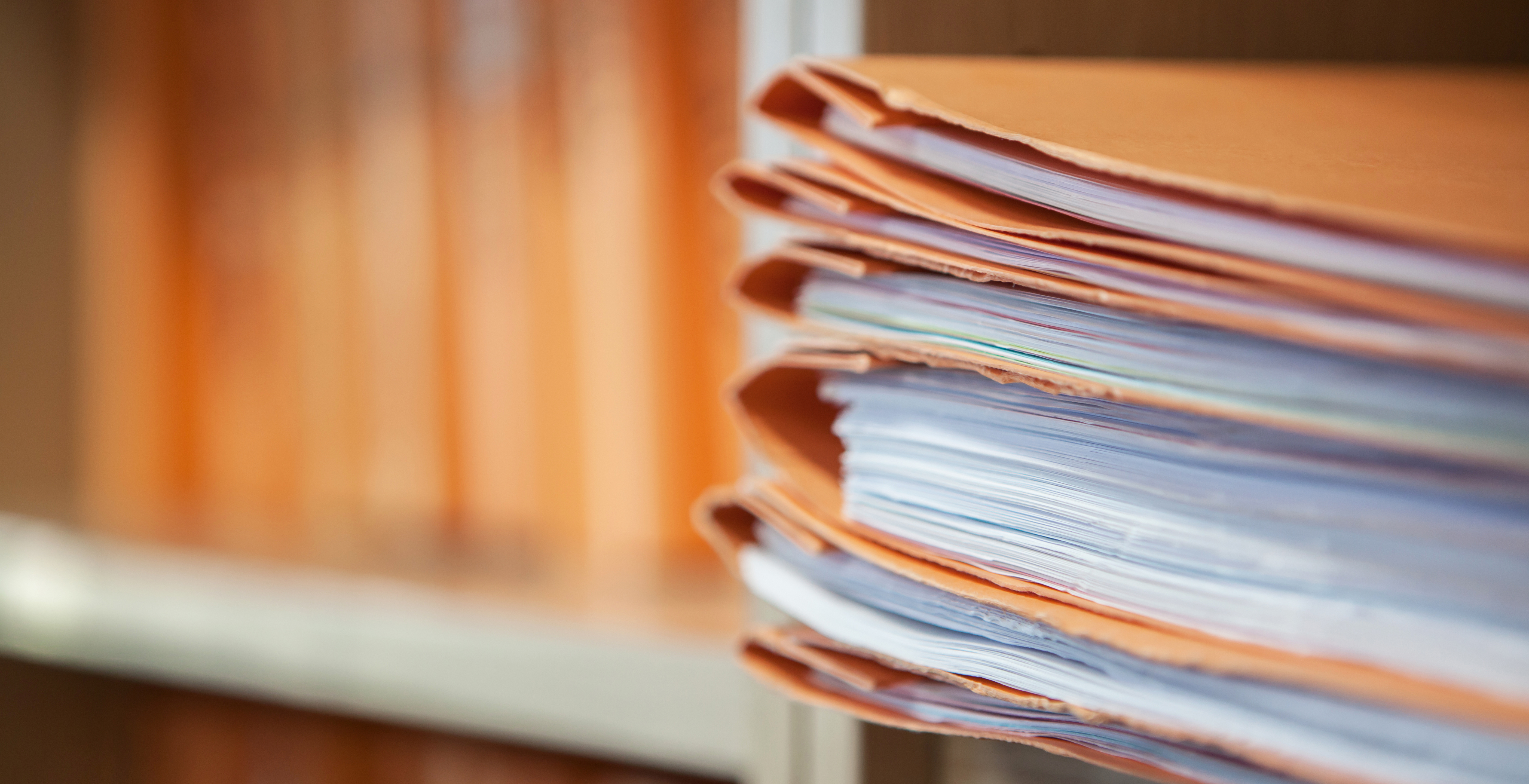 Close up of a stack of manila file folders with white pages inside