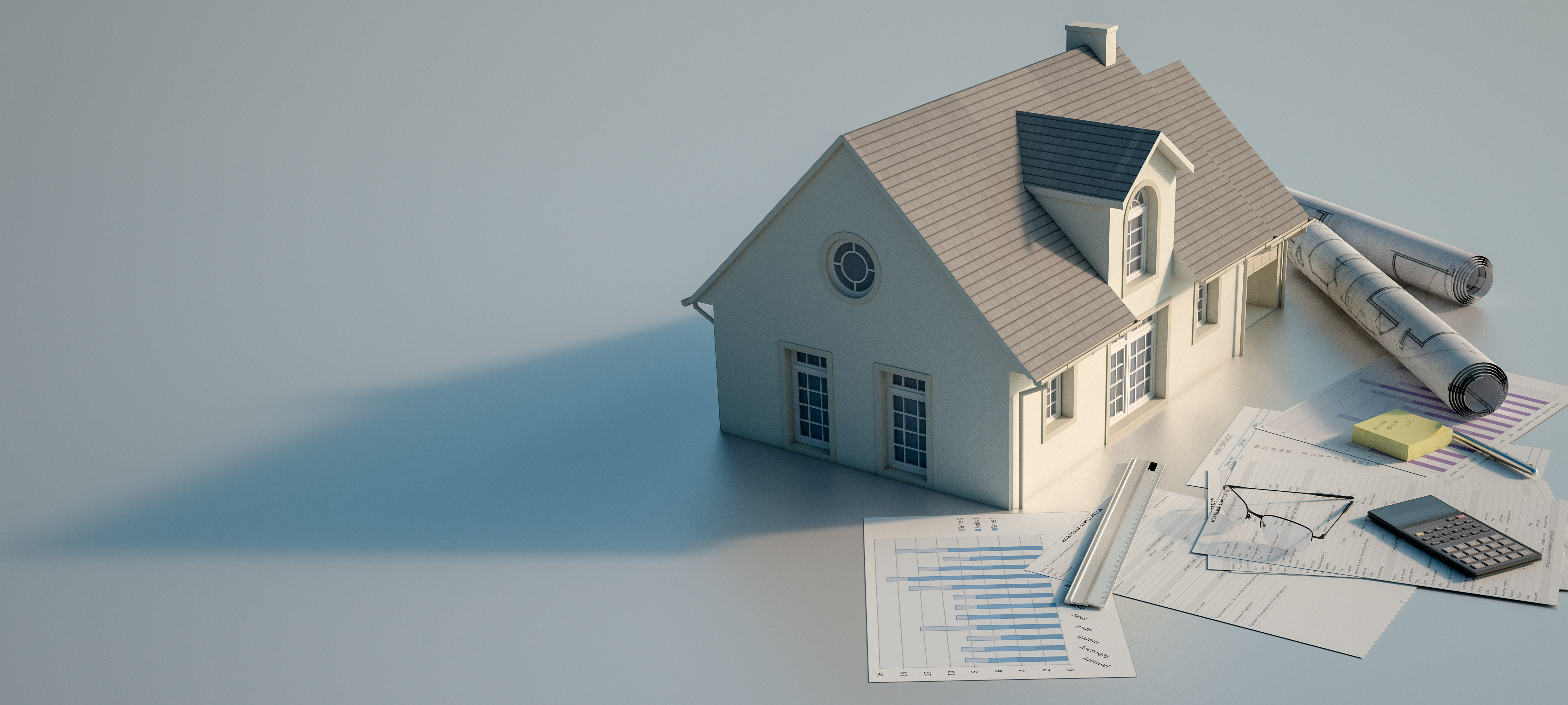 Small model house next to papers, sticky notes, a calculator, a ruler, a pair of glasses and rolled up posters.