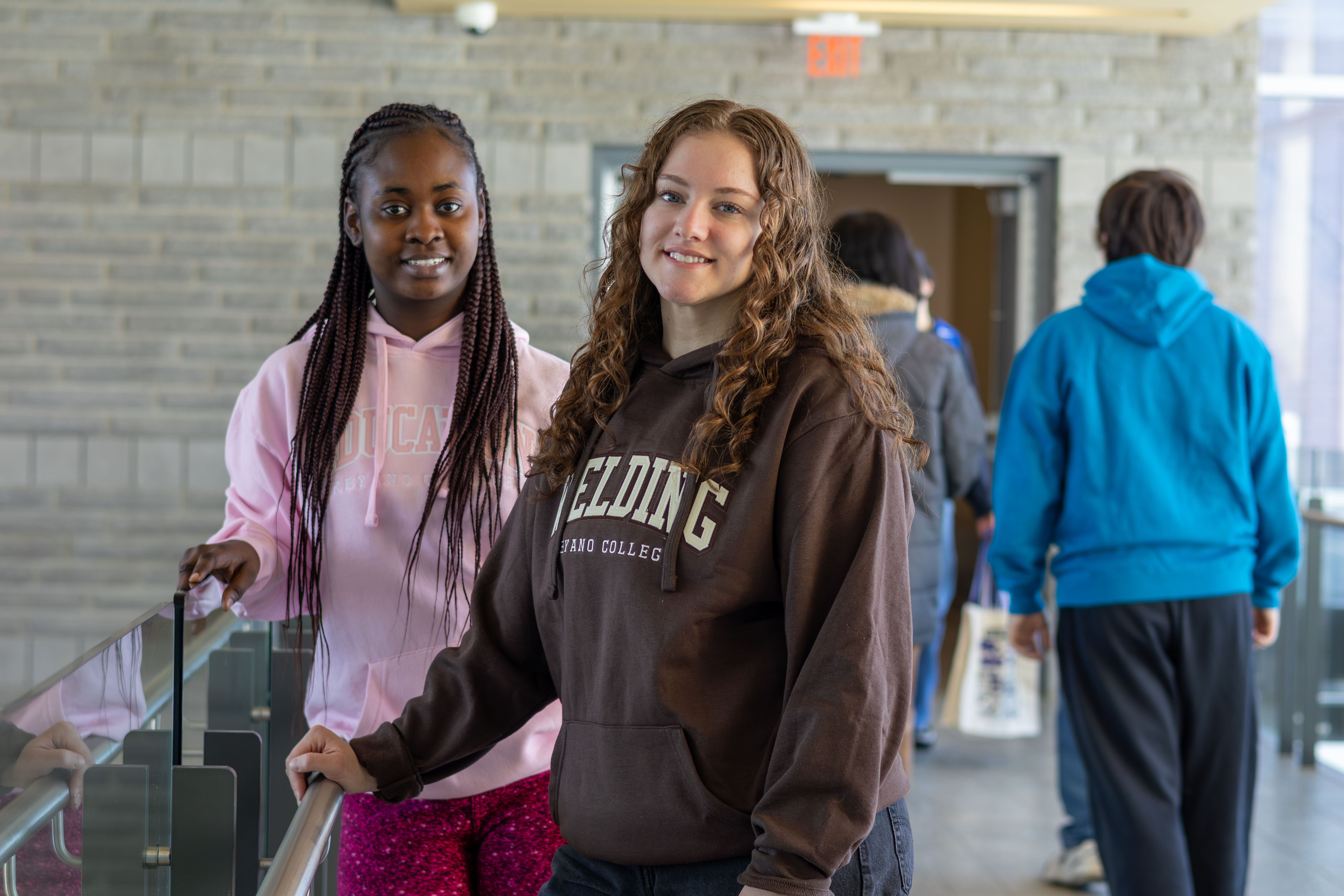 Two girls leaning on the handrail smiling for picture