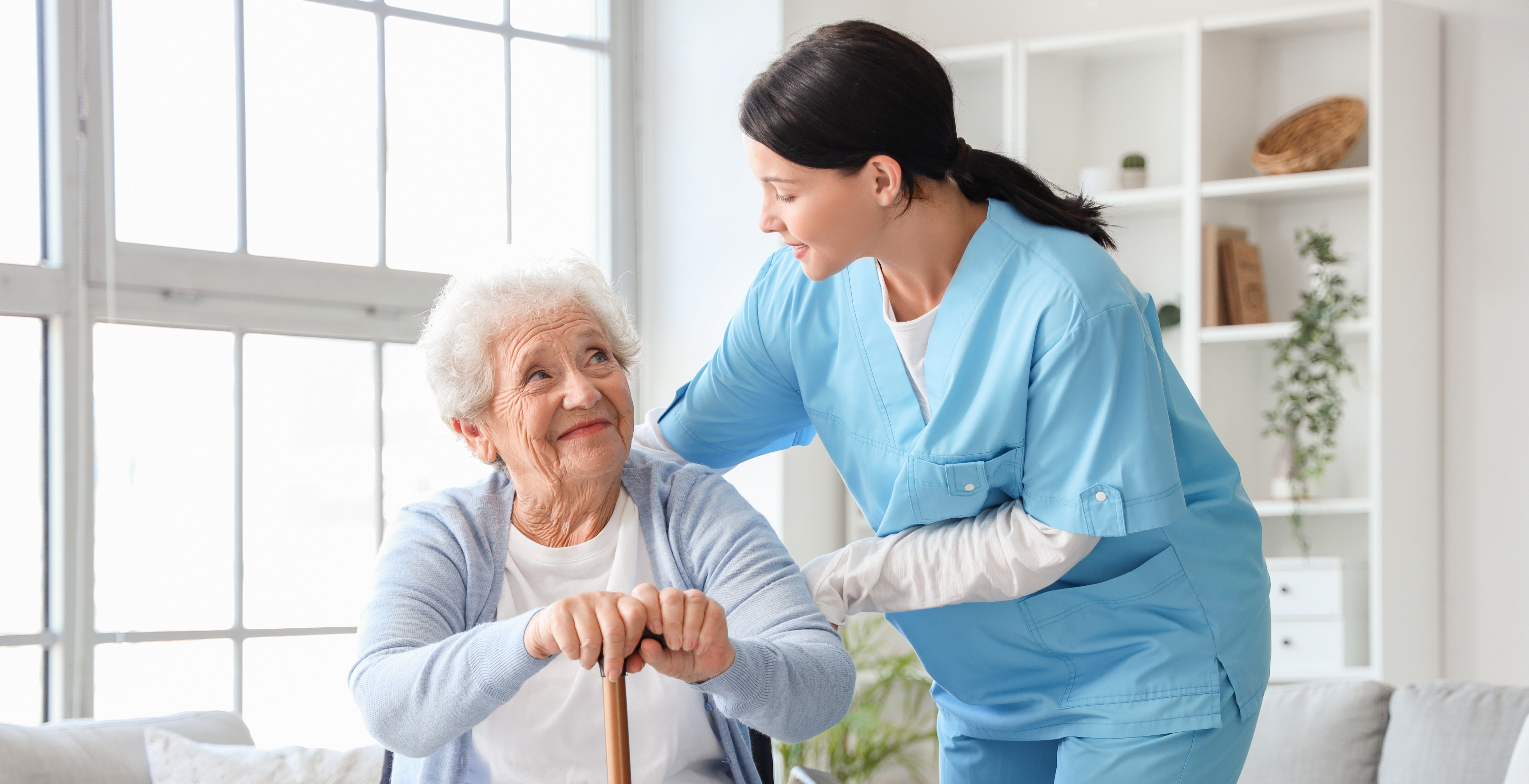 Senior woman with stick and nurse at home