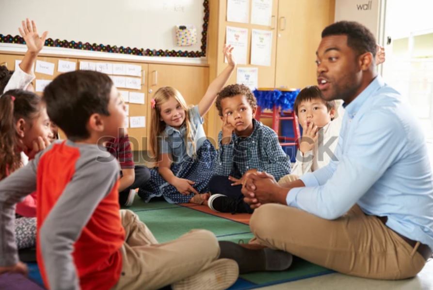 A teacher sitting on the floor with students