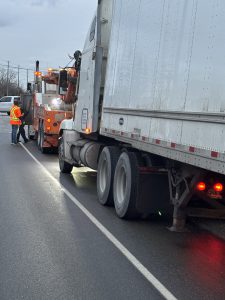transport truck with tow truck in front of it