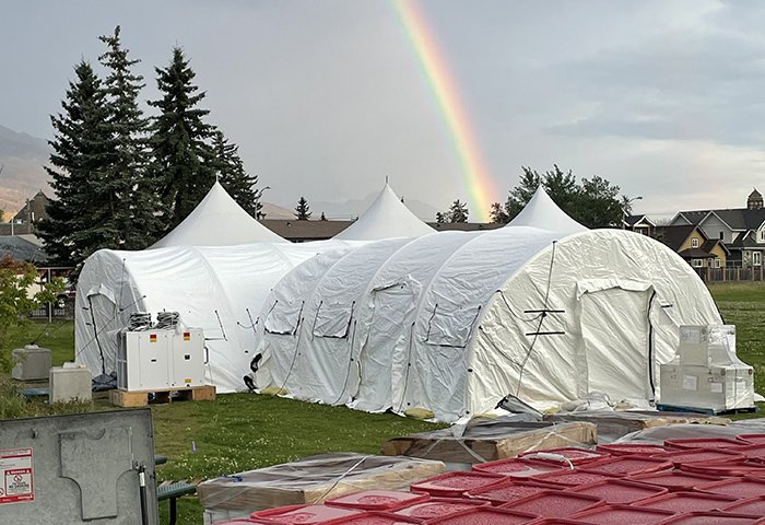 A rainbow against a dark, cloudy sky hangs over the large tent that is a part of the re-entry support centre