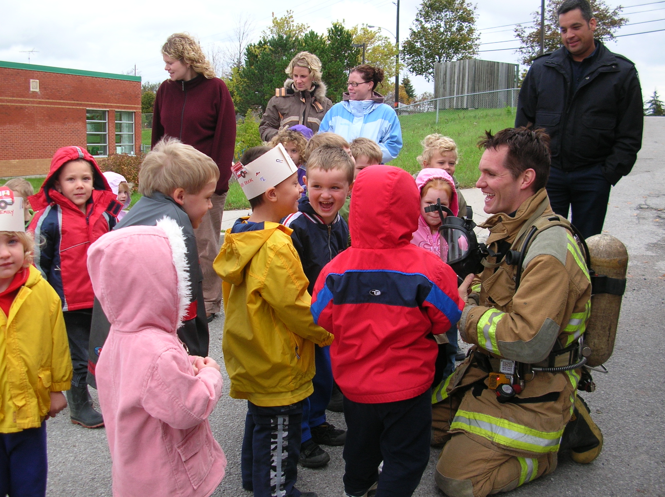 A firefighter smiles, talking with young students
