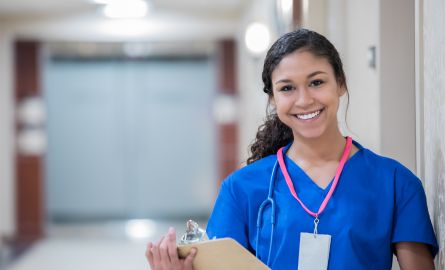A medical student smiling, holding chart