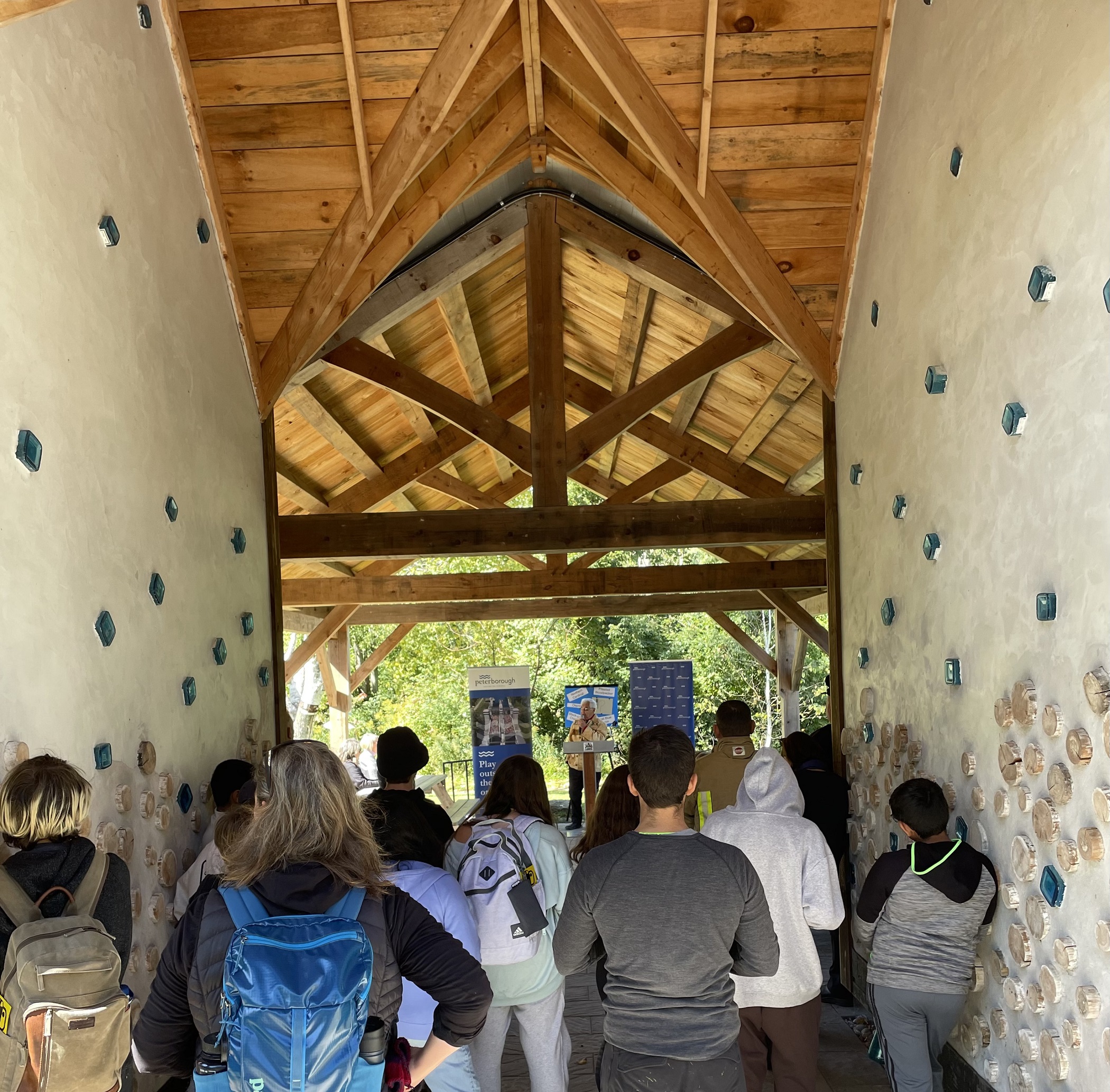 A group listens to opening remarks under the Ecology Park pavilion