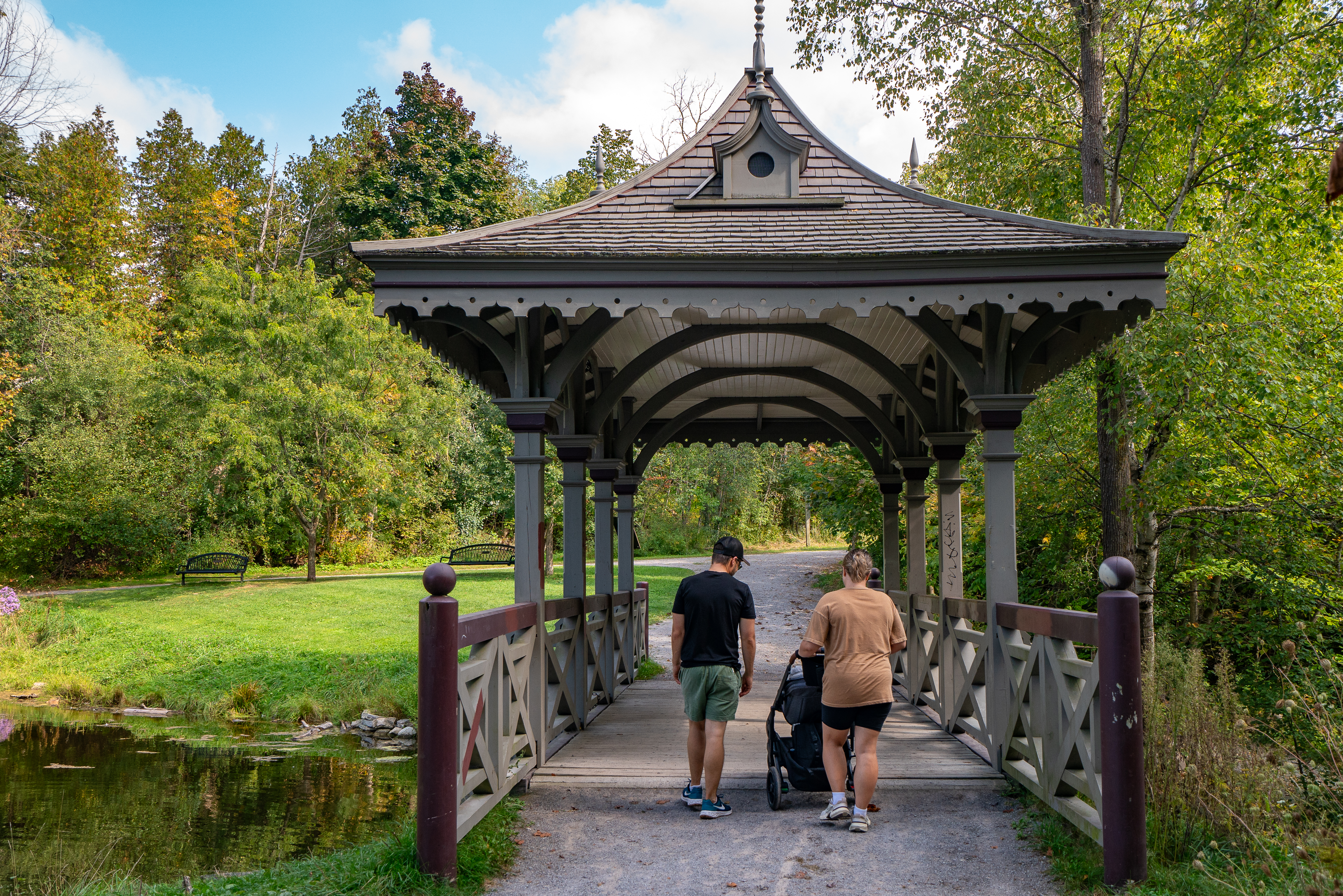 Family with stroller walks across covered bridge in Jackson Park on a sunny spring day