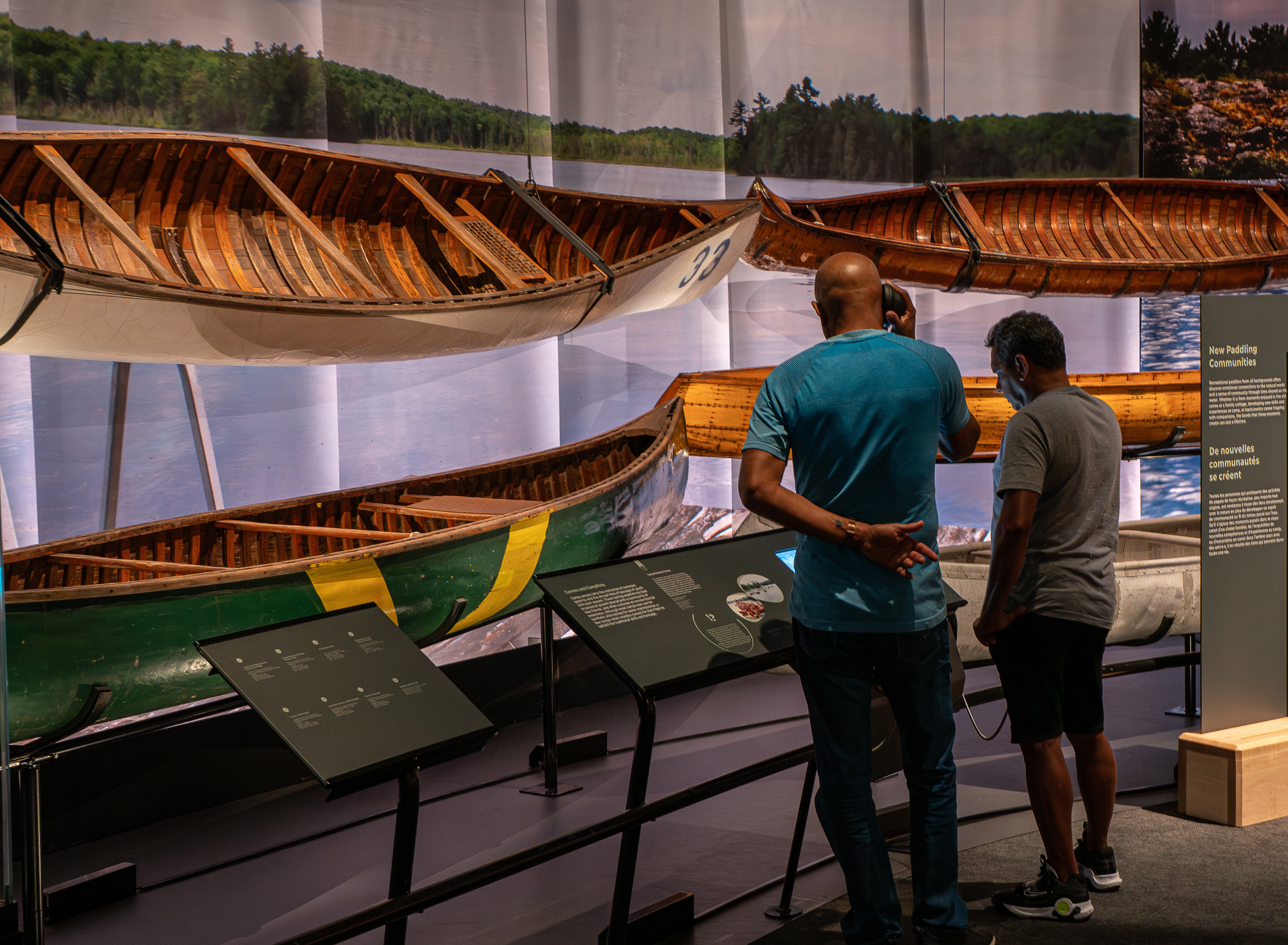 Two people looking at canoes on display in a museum