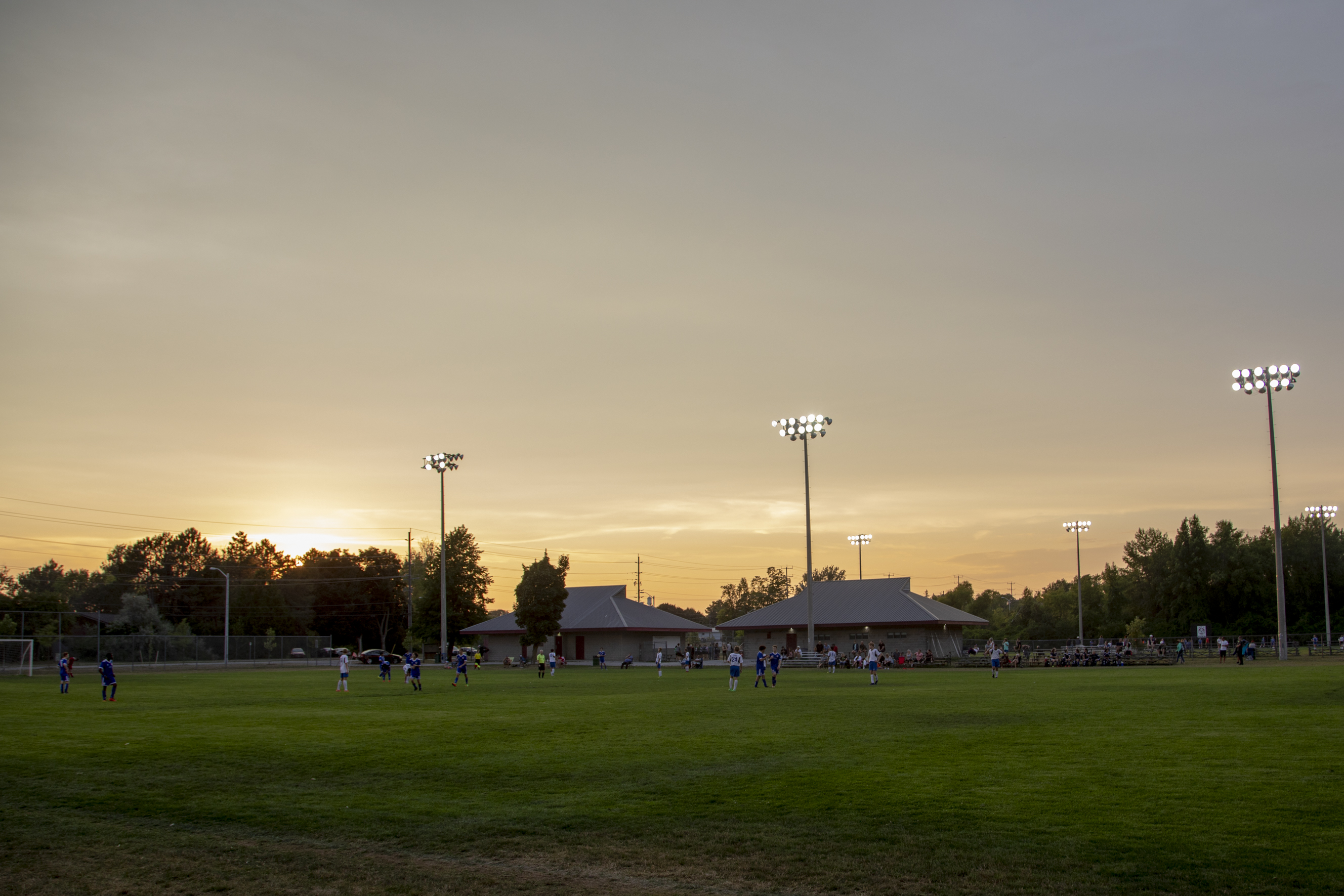 A soccer game at Eastgate Park while the sun is setting