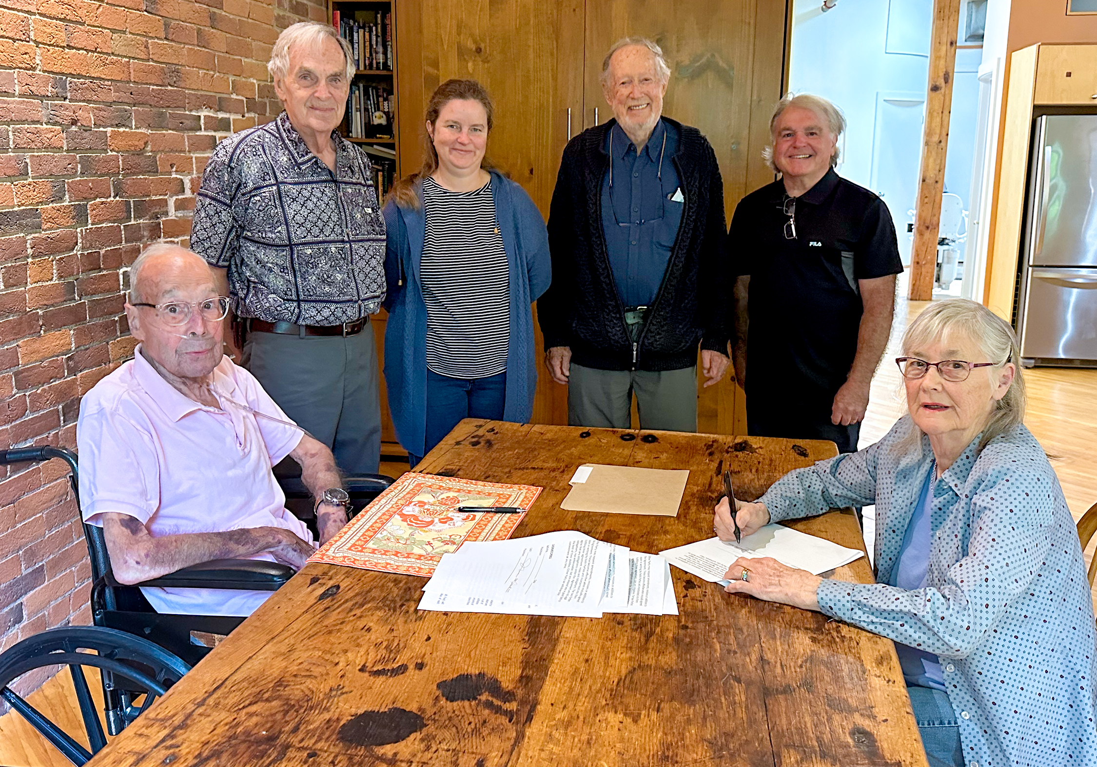 People sit and stand around table with papers