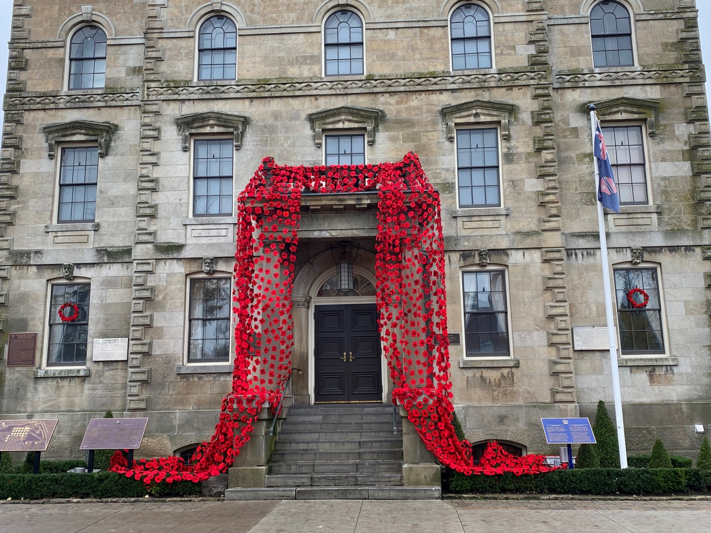 Hundreds of knitted red poppies cascade down a heritage building