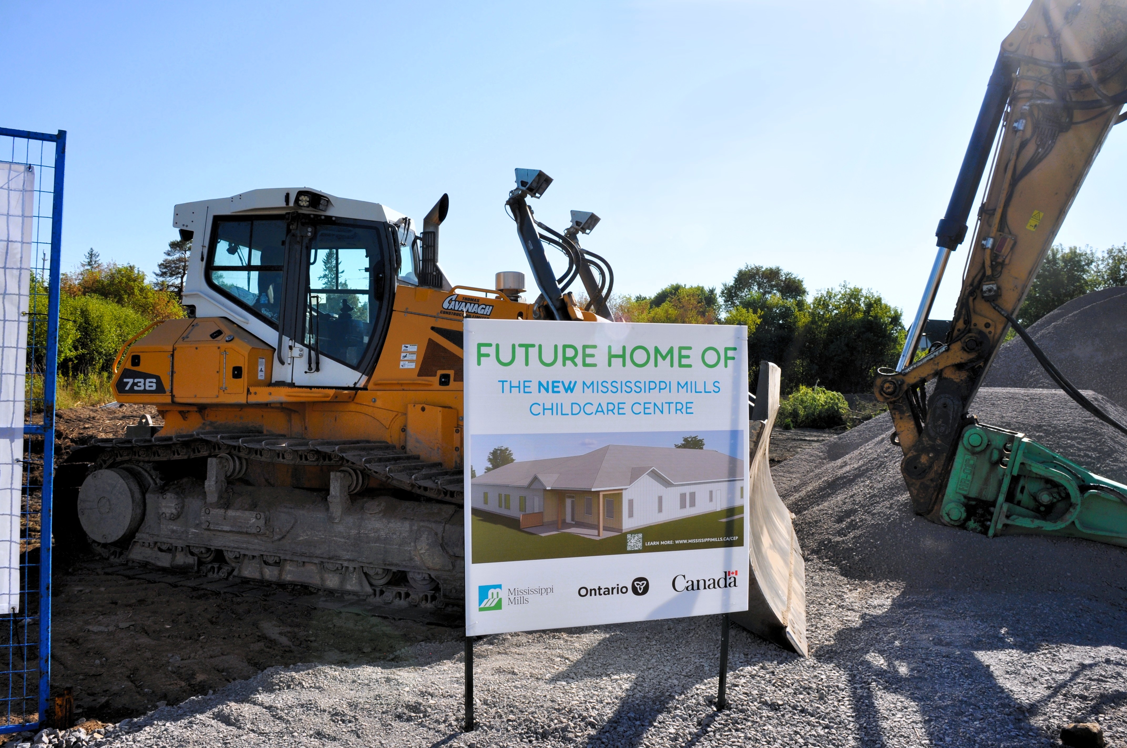 bulldozers behind a sign that reads "future home of the new childcare centre"