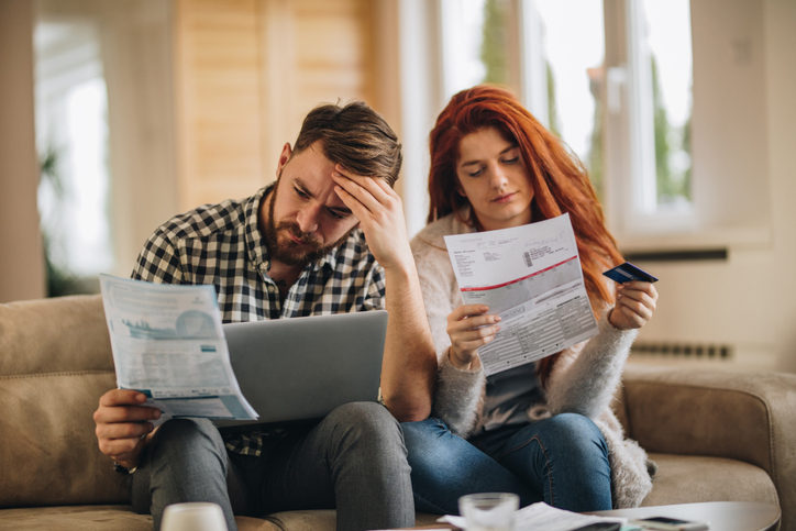 Couple sit on couch looking at bills