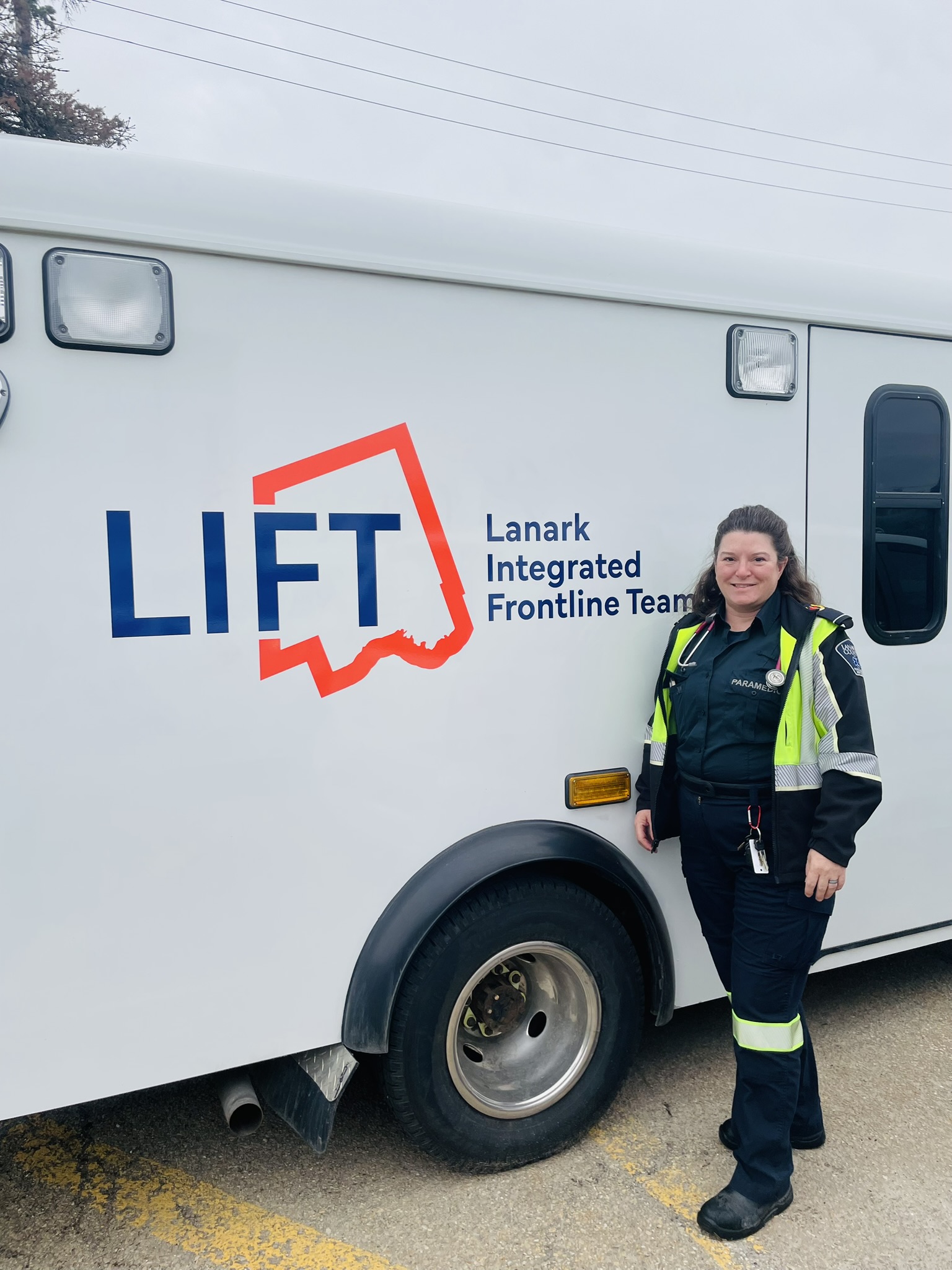 A paramedic stands next to a vehicle with the logo 'LIFT - Lanark Integrated Frontline Team'