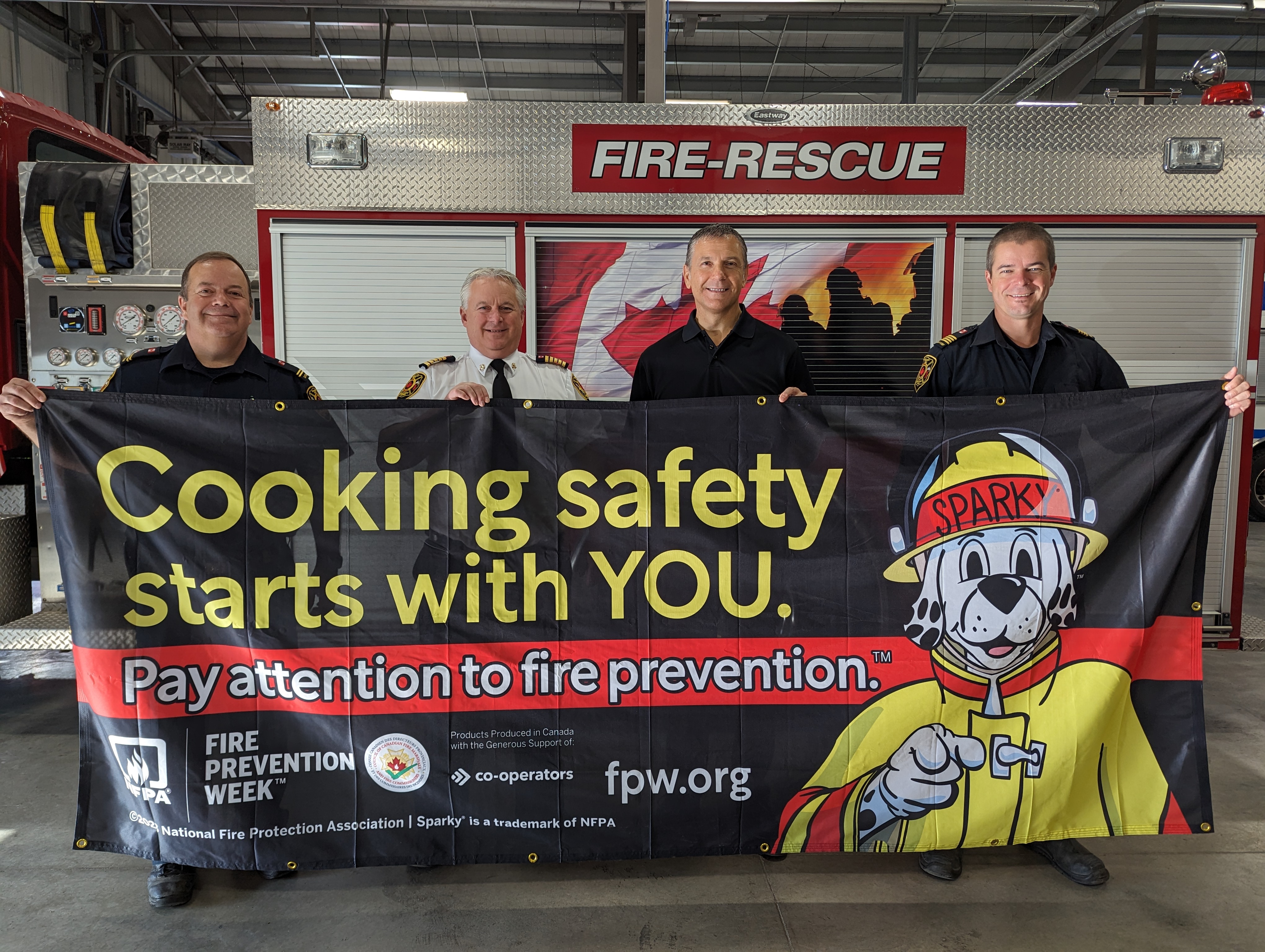 Four people hold a fire prevention banner
