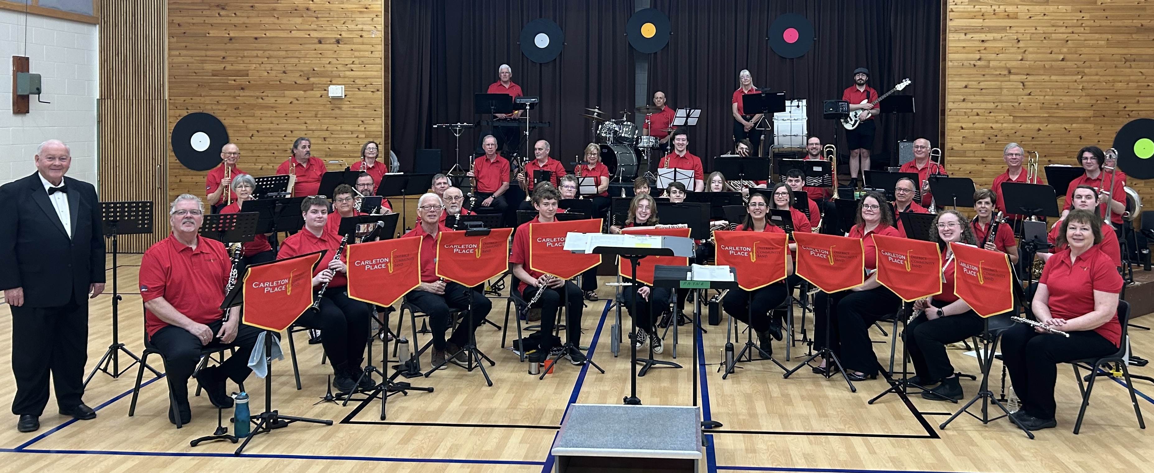 Photo of band members wearing red shirts and black pants seated in a group.