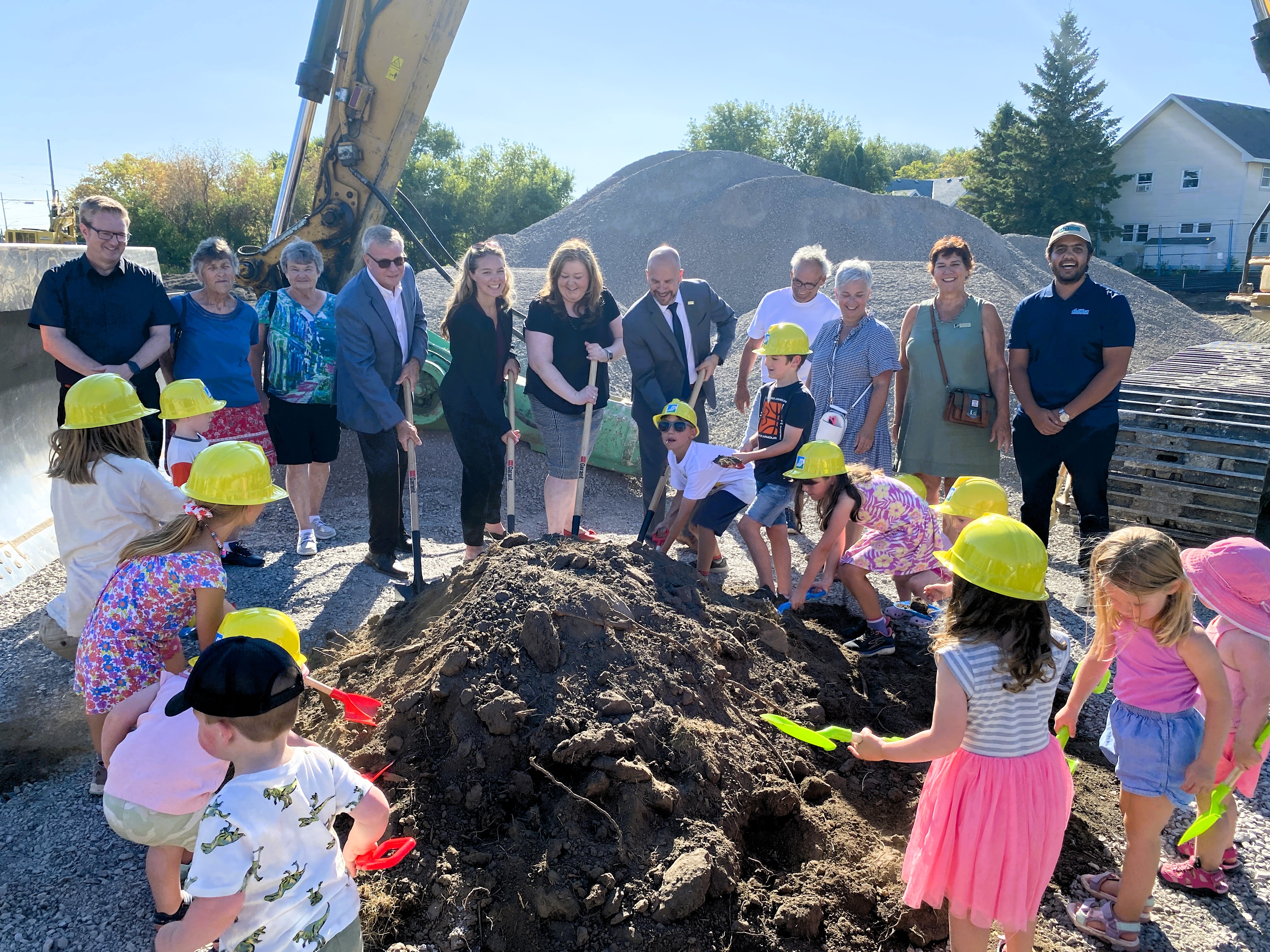 Group photo of kids and community representatives putting shovels into the ground