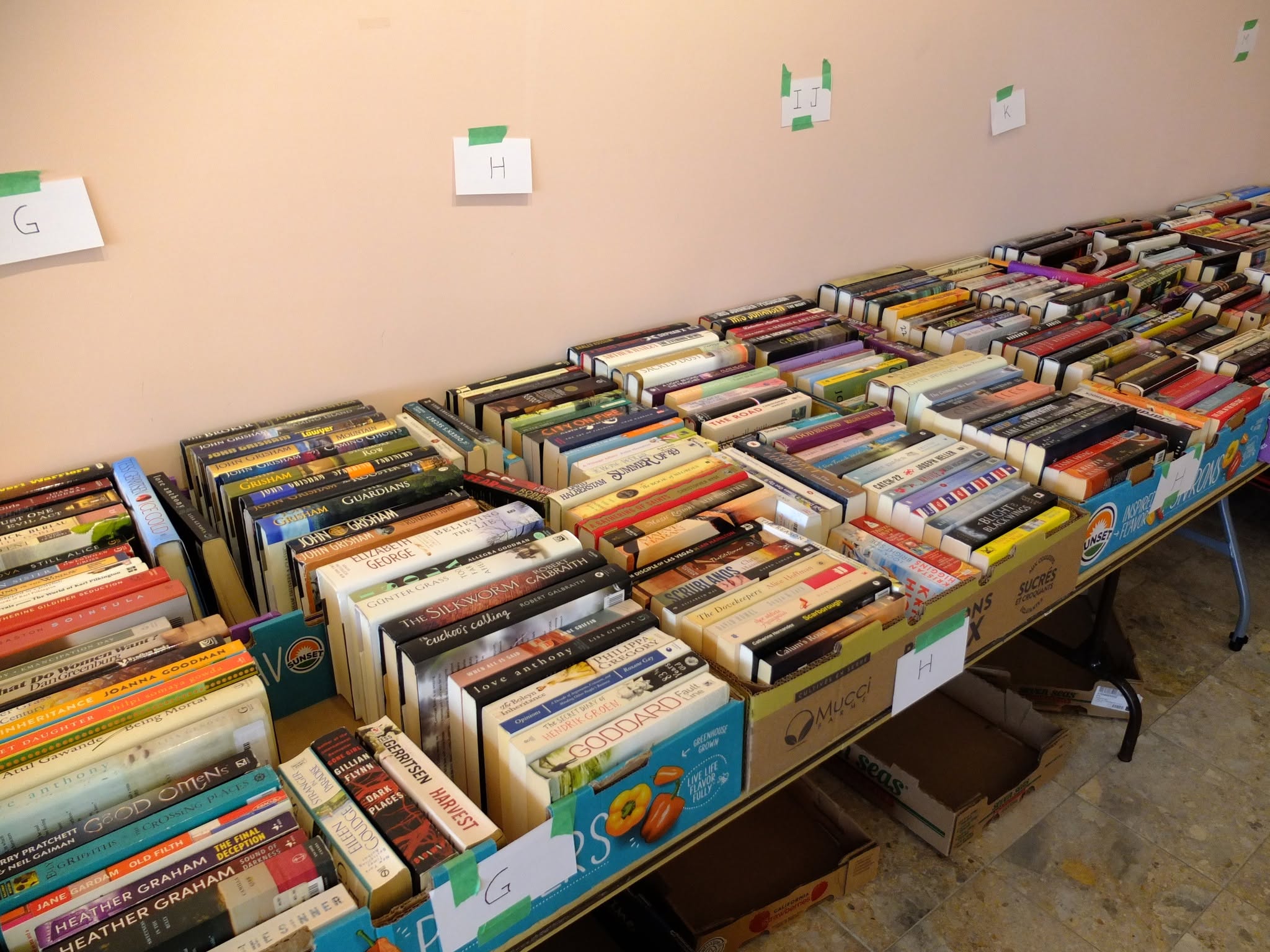 Tables lined against a wall with boxes of paperback books in them