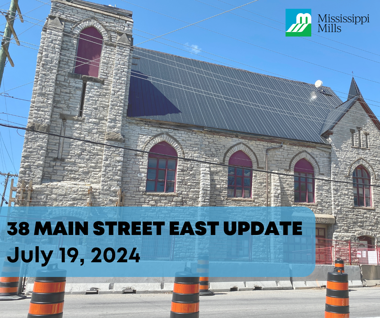 Photo showing a stone building with concrete barriers and orange pylons in front. Text reads '38 Main Street East Update: July 19, 2024'