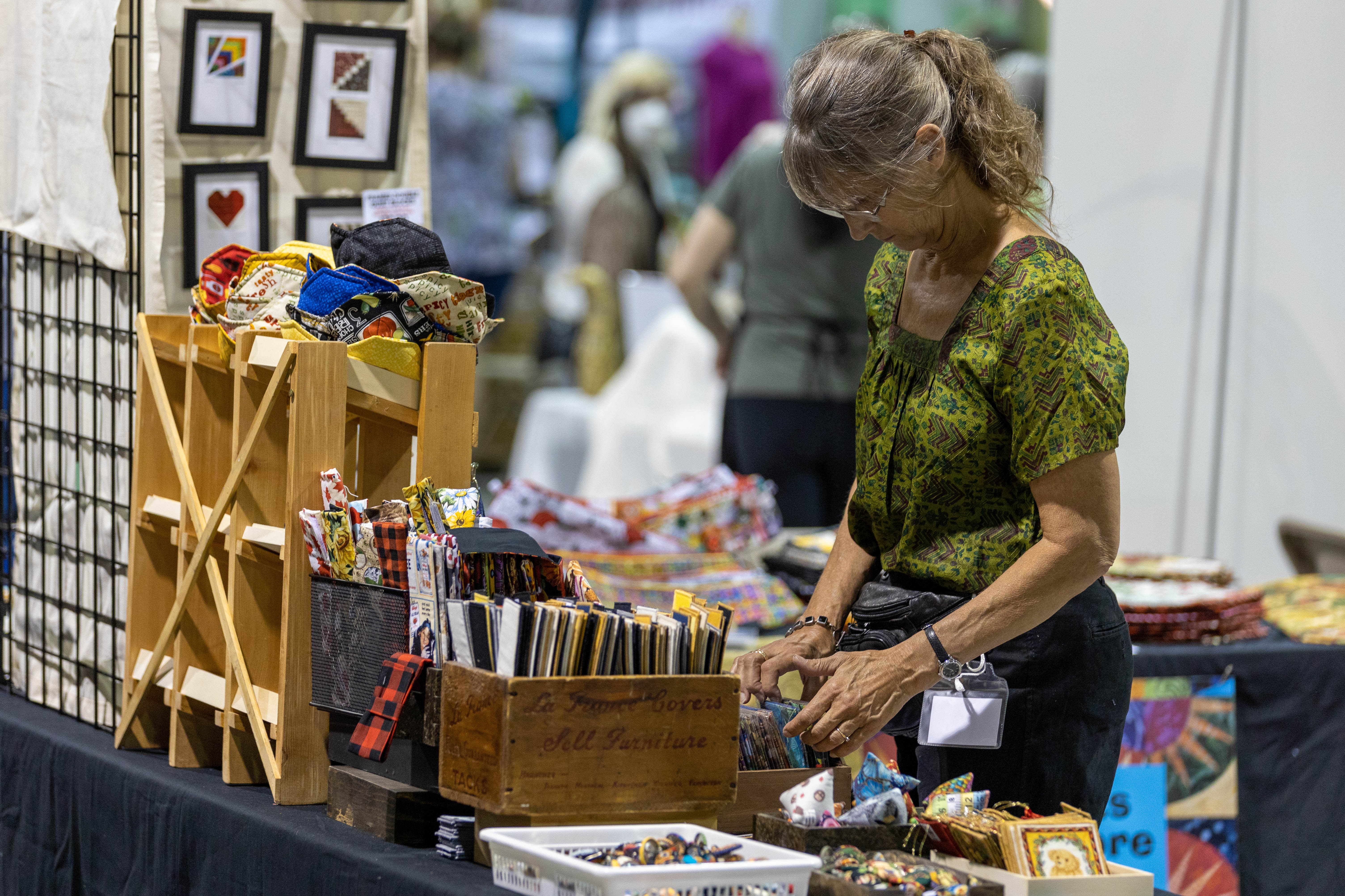 A woman arranges fabric samples in a display on a table
