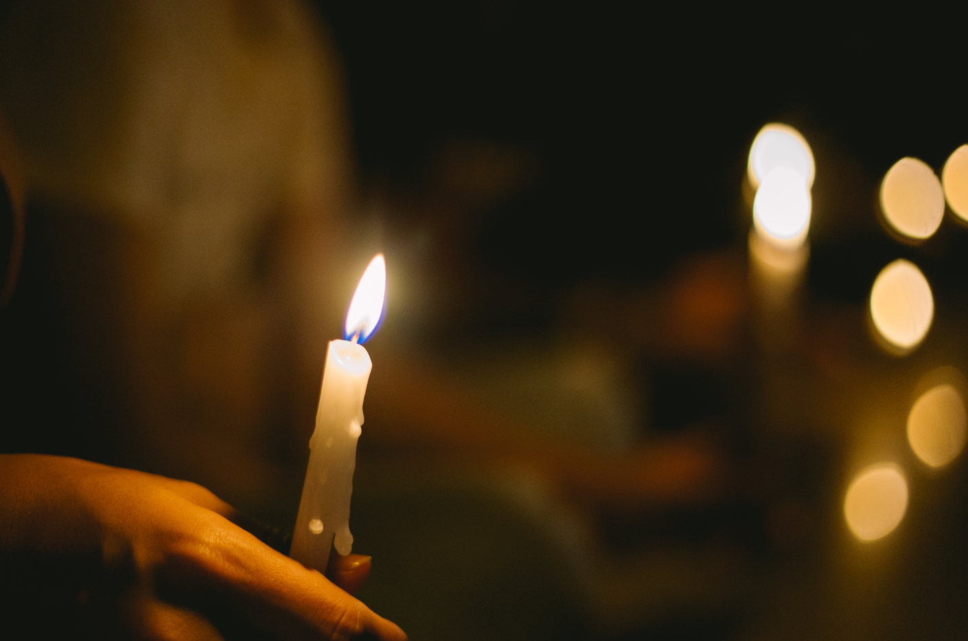 Person holds a lighted candle at vigil