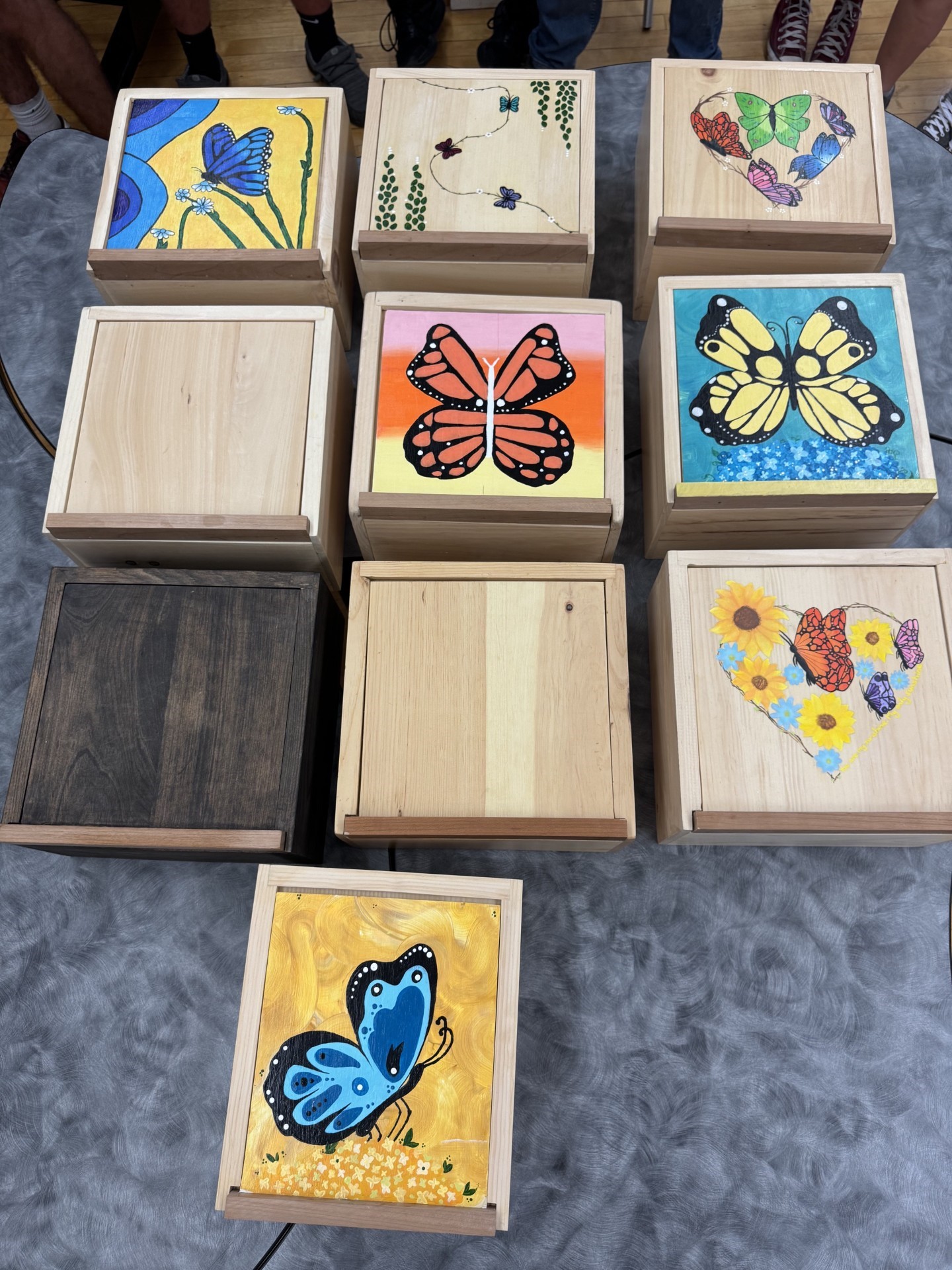Ten square wooden boxes with brightly coloured scenes
