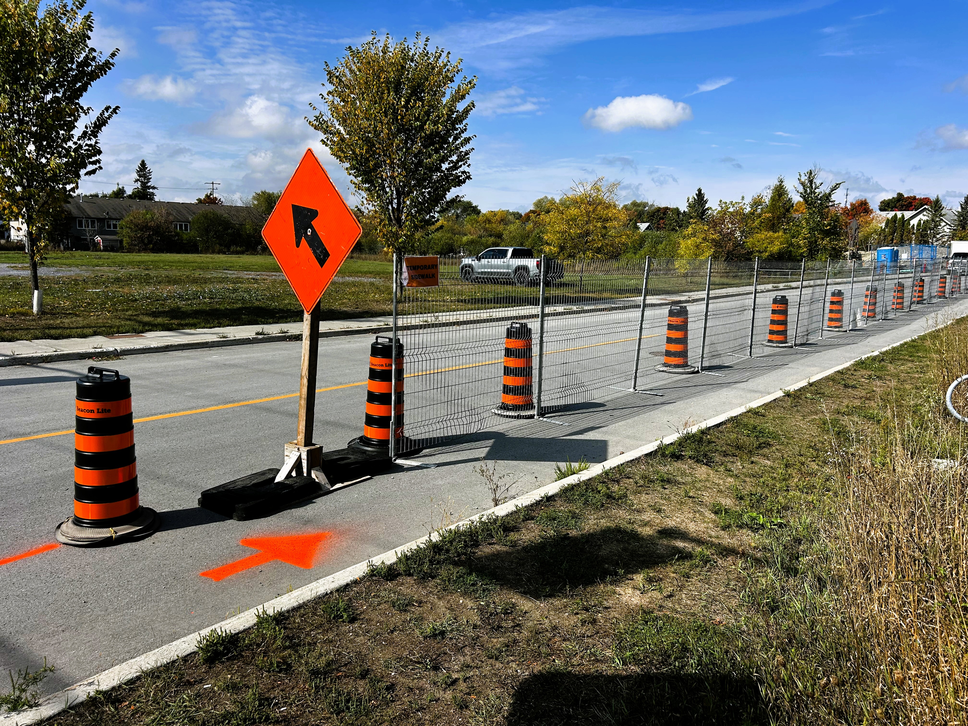 Photo showing fenced temporary sidewalk with signage on a street