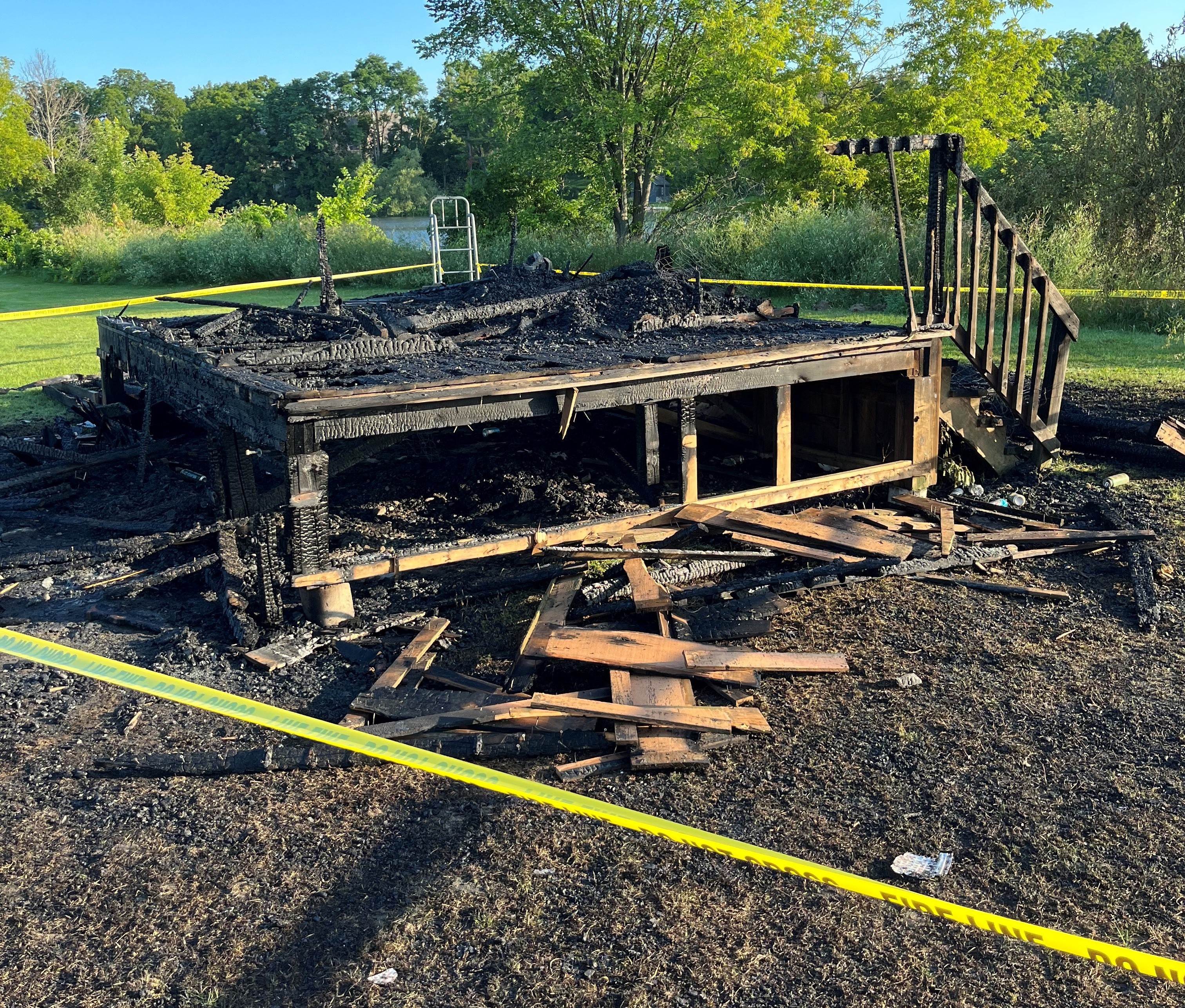 Yellow caution tape surrounds a burned structure