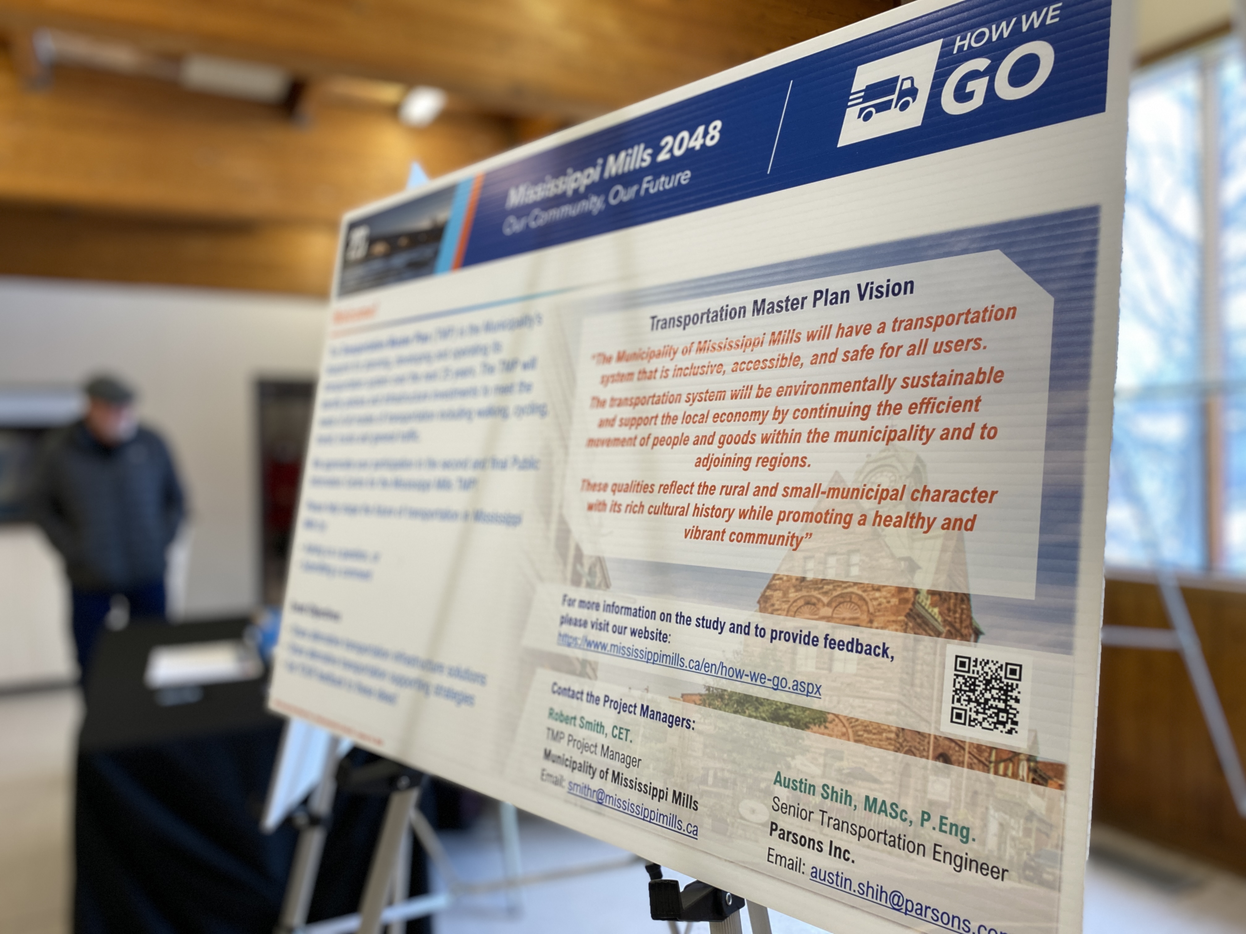 Close-up photo of information board on an easel with a man standing in the background