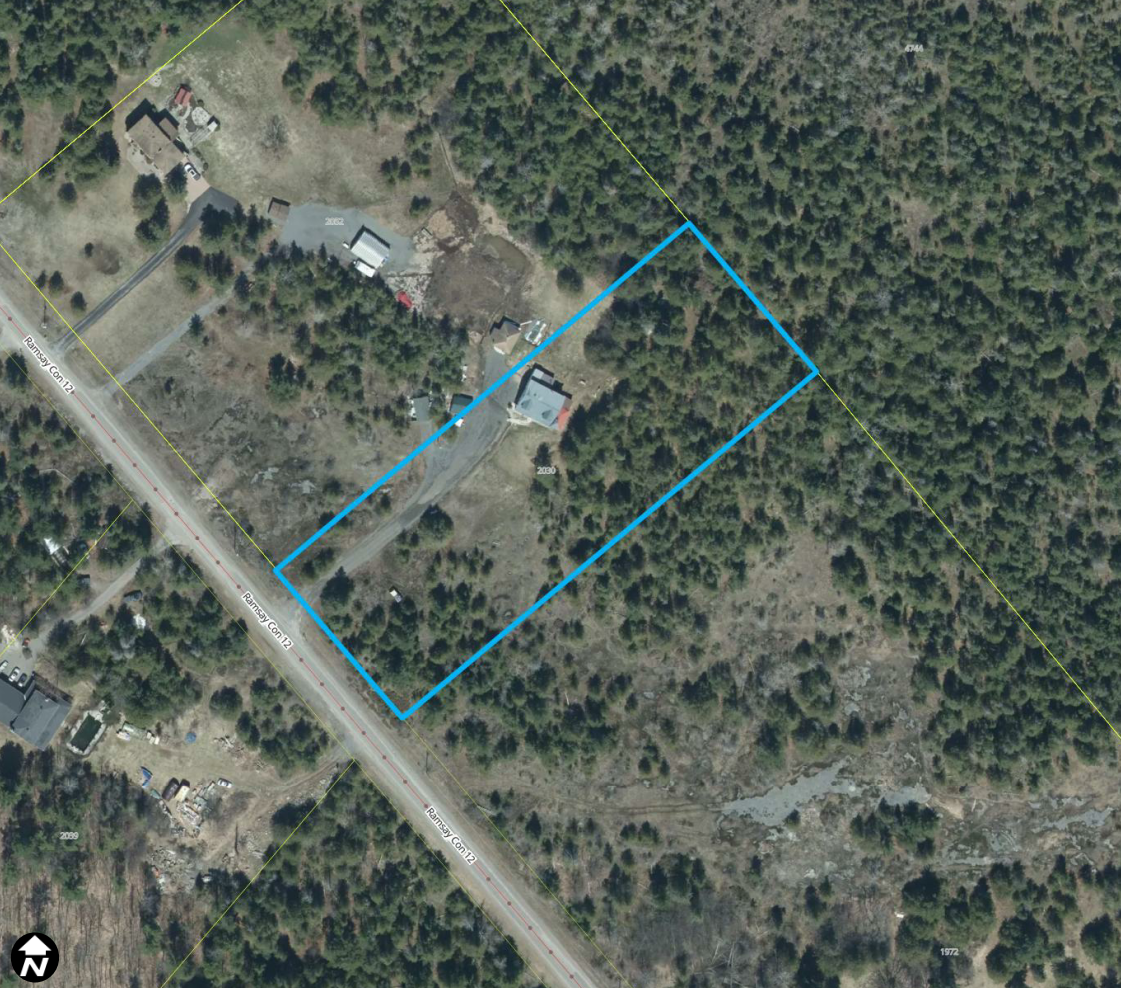 Satellite image showing a rural area with lots of trees and a property marked in blue.