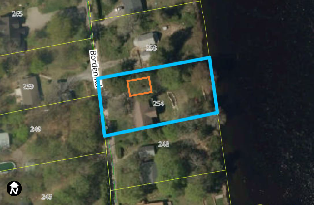 Satellite view of a rural area with a property outlined in blue with a smaller portion inside the blue area outlined in orange.