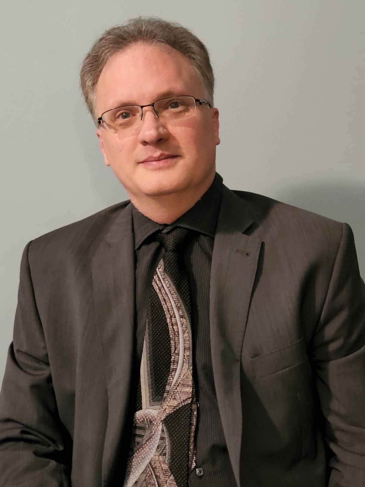 Headshot of a man with glasses in a business suit