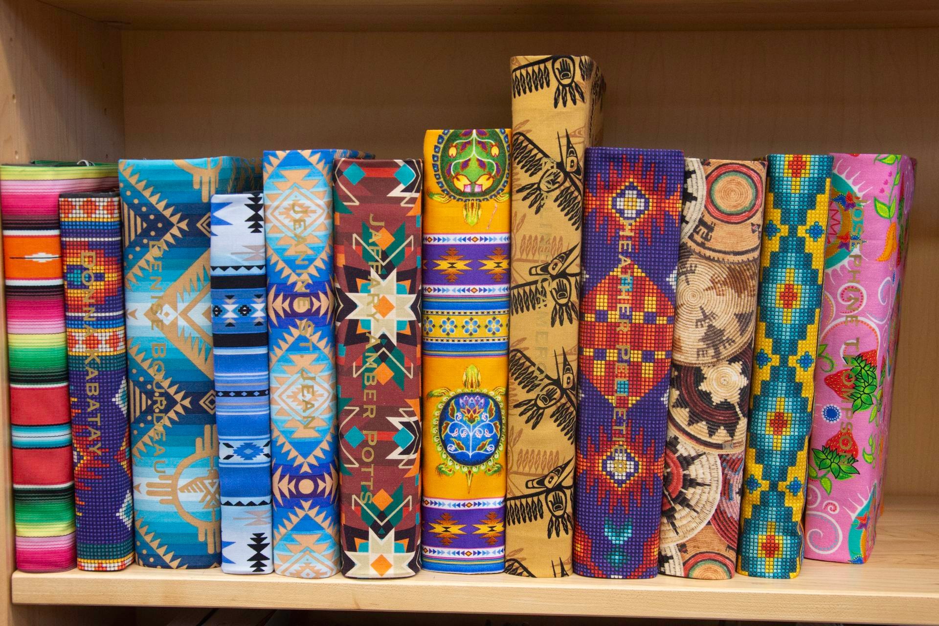 Row of books on a shelf bound in brightly coloured textiles