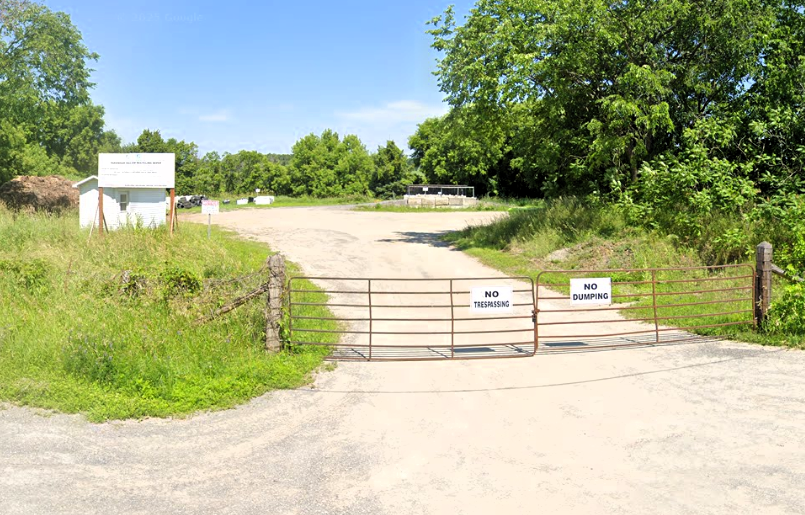 A gated rural property with a large white sign behind the gate